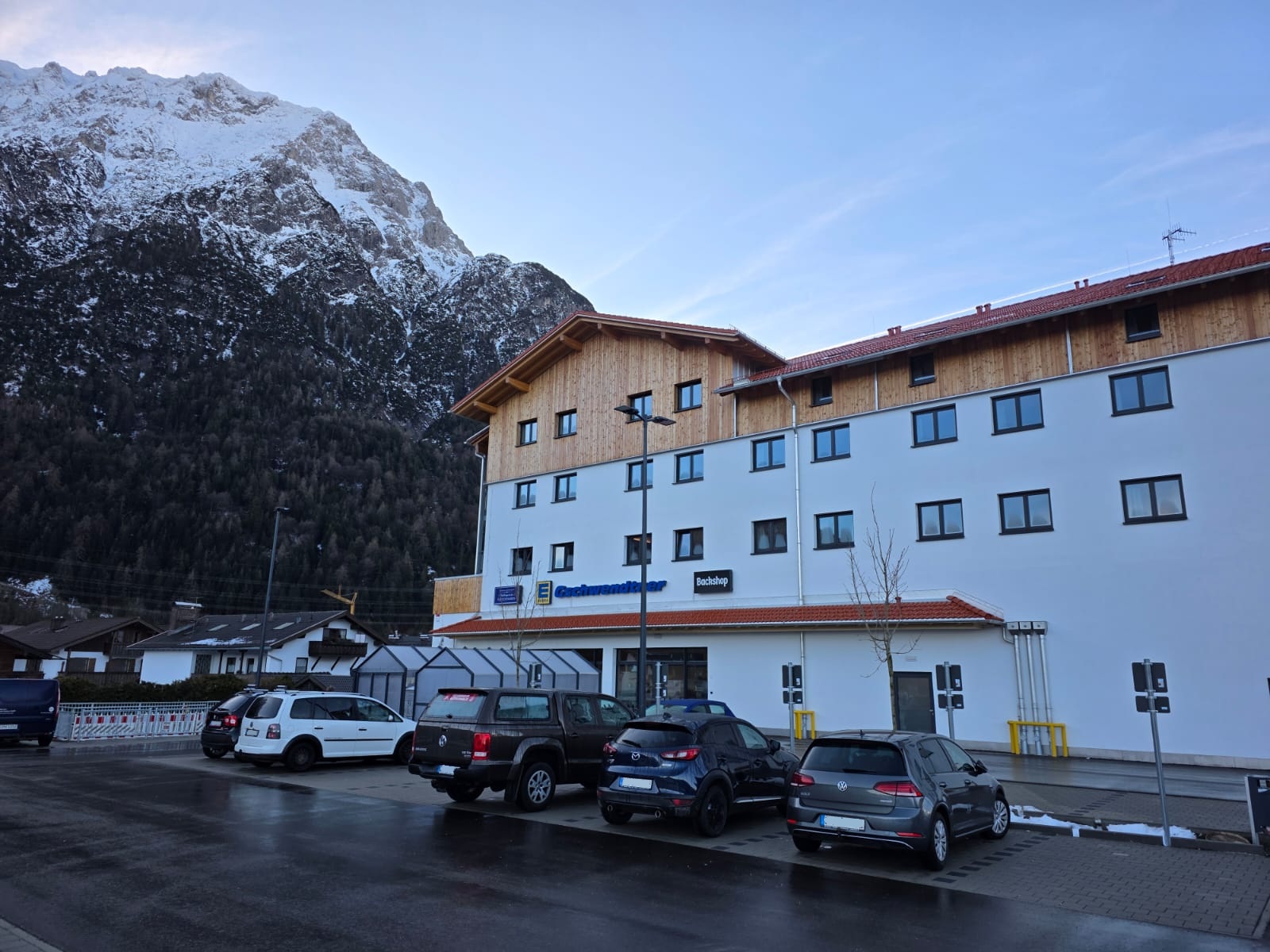 Außenansicht des Neubaus von Edeka Mittenwald mit Kundenparkplatz vor Bergkulisse in Mittenwald.