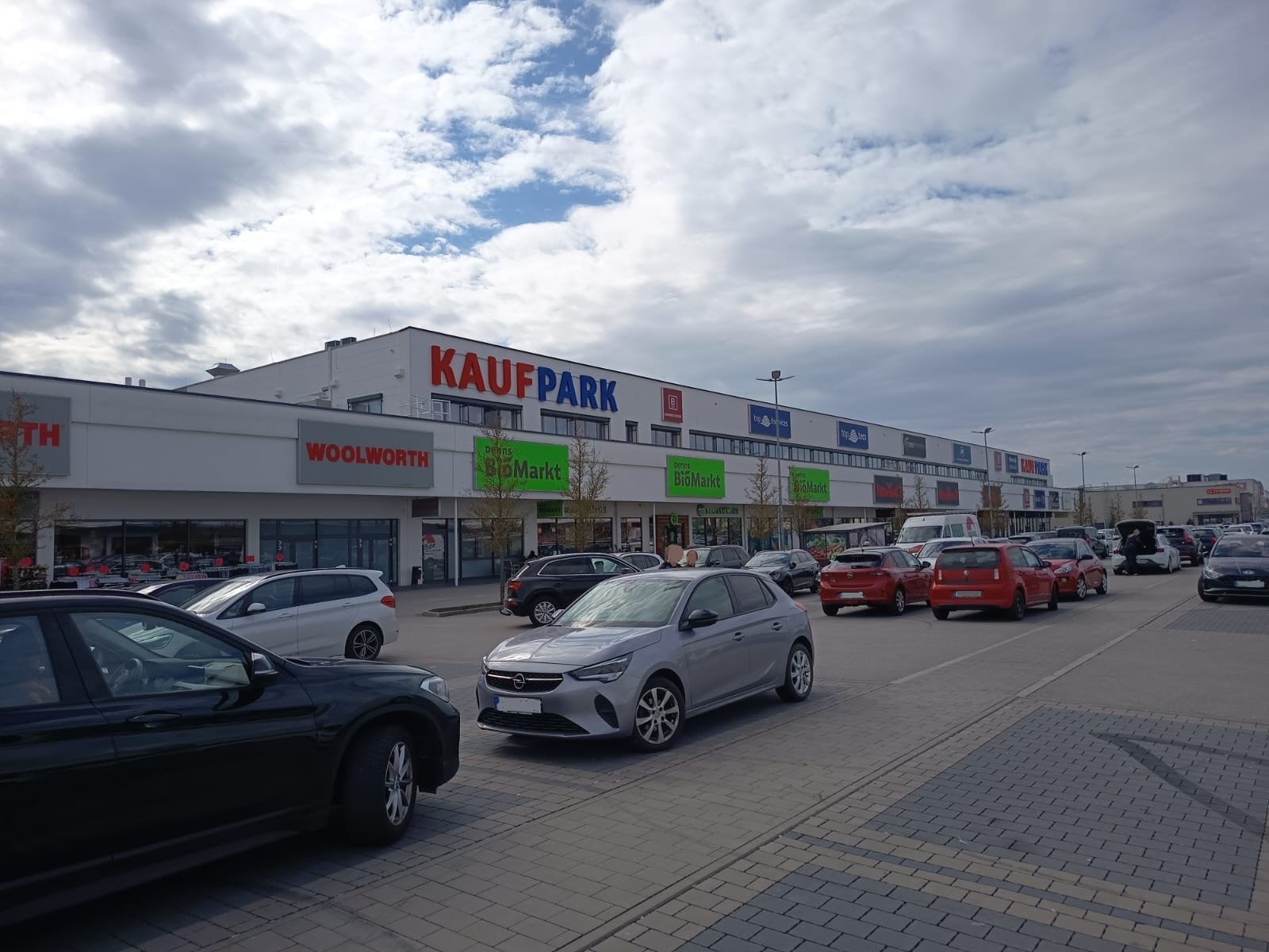 Außenansicht des neu errichteten Fachmarktzentrums Neutraubling mit Parkplatzflächen und Ladenfassaden in Neutraubling.