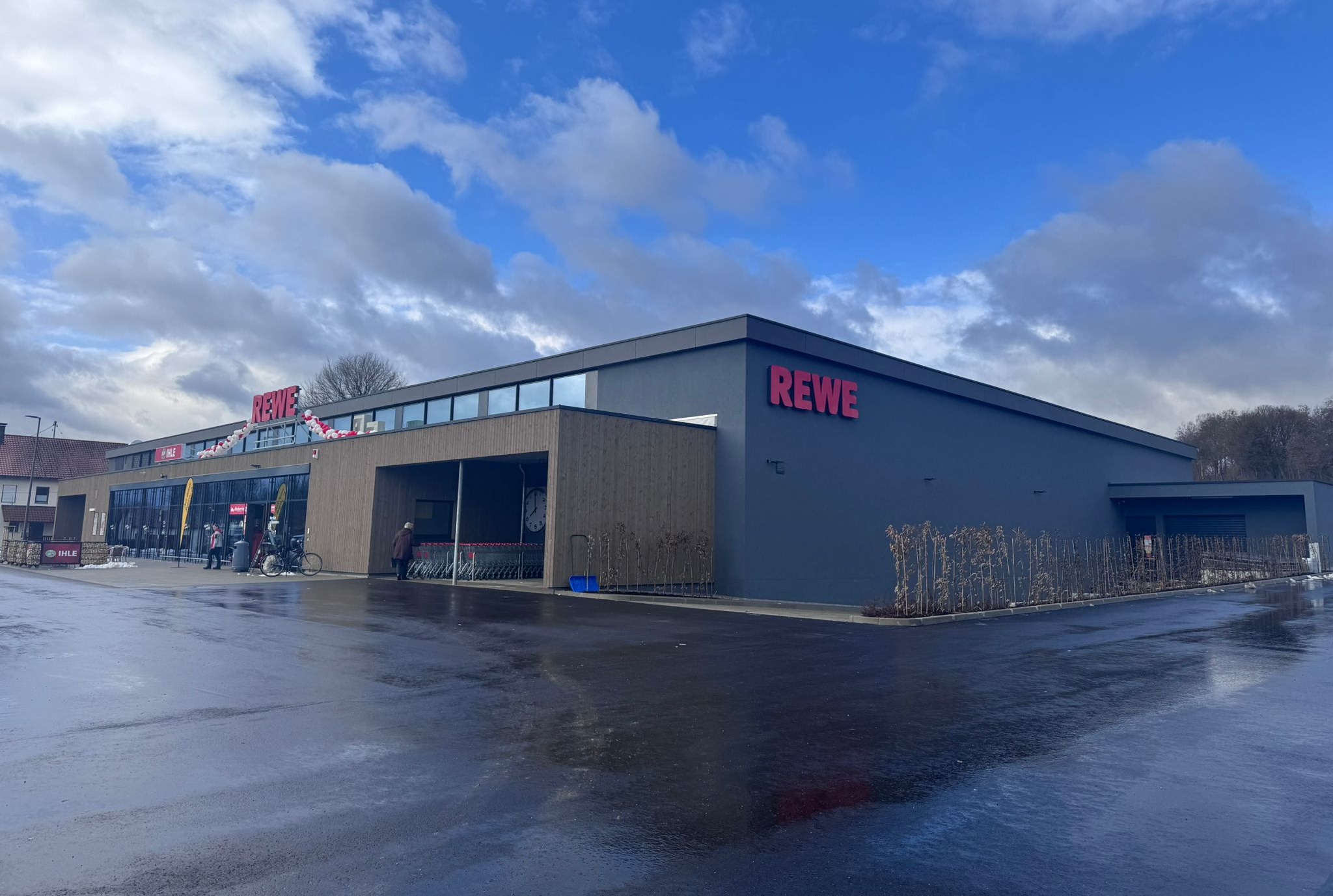 Außenansicht des neu errichteten Rewe-Marktes in Marxheim mit Eingangsbereich und Parkplatz.